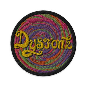 May include: Embroidered patch with a black border and a colorful, swirling design in shades of pink, orange, green, and purple. The word "Dysstone" is embroidered in yellow, stylized lettering, centered on the patch.