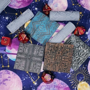 May include: A set of six gray and brown patterned tiles with a blue and gray patterned tile. The tiles are surrounded by red dice with black numbers. The background is a purple fabric with gold stars.