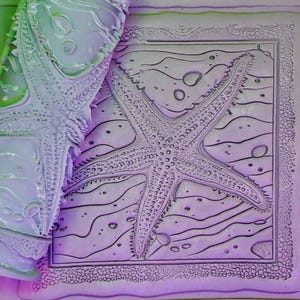 May include: A purple rubber stamp with a detailed design of a starfish on a wavy background. The stamp is surrounded by a decorative border.