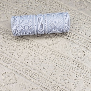 May include: A gray rolling pin with a geometric pattern. The pattern is a repeating design of triangles, squares, and diamonds.