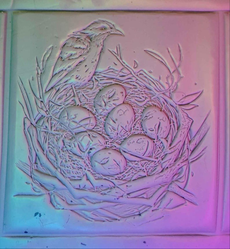 K&ouml;nnte beinhalten: Eine wei&szlig;e Keramik-Reliefskulptur eines Vogels, der auf einem Nest mit Eiern sitzt. Der Vogel sitzt auf einem Ast und hat die Fl&uuml;gel ausgebreitet. Die Eier sind in einem Kreis um den Vogel angeordnet.