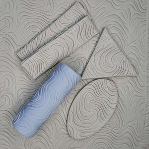 May include: A set of five gray textured clay stamps with a wavy pattern. The stamps are in different shapes, including a rectangle, a triangle, an oval, and a roller.