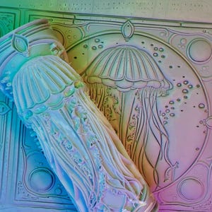 May include: A close-up of a white ceramic relief sculpture of a jellyfish with a detailed design. The sculpture is in a light blue and purple color scheme.
