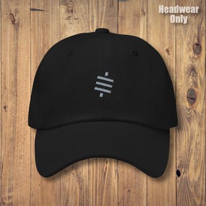 Könnte beinhalten: Schwarze Baseballkappe mit gebogenem Schirm. Die Kappe hat ein silbernes Stickdesign auf der Vorderseite und den Text "Headwear Only" in Weiß. Der Hut ist vor einem Holzgrund platziert.