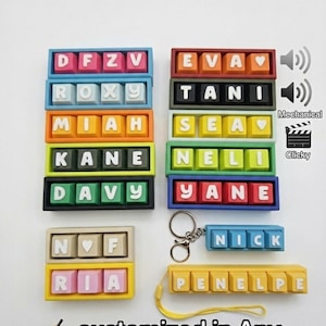 Könnte beinhalten: Eine Sammlung farbenfroher, personalisierter Namensschilder mit Tastenkappen. Jedes Schild zeigt einen Namen oder Initialen in weißen Buchstaben. Der Text "customized in Any color and Any letters" ist ebenfalls enthalten.