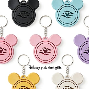 May include: A selection of Mickey Mouse head-shaped keyrings in various colours. Each keyring has a circular emblem with a stylized design and a metal ring. Colours include black, blue, pink, purple, yellow, and white.
