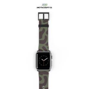 May include: An Apple Watch with a camouflage-patterned strap in green and brown hues. The watch face shows the time. The strap is fastened with a black buckle. The text "1580 ONE FIVE EIGHTY CO." is at the top.