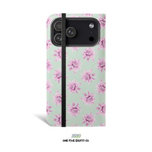 Op de afbeelding: Een telefoonhoesje met een bloemenpatroon. De hoes heeft een lichtgroene achtergrond met een patroon van roze bloemen. Een zwarte elastische band houdt de hoes gesloten. De tekst "1580 ONE FIVE EIGHTY CO." staat onderaan.