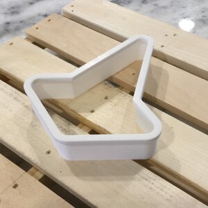 May include: White plastic cookie cutter shaped like an arrow pointing to the left.