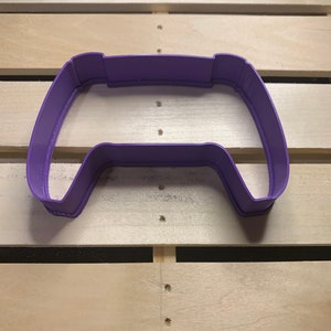 May include: Purple plastic cookie cutter shaped like a video game controller.
