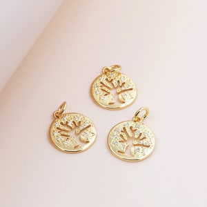 Puede incluir: Tres abalorios de tono dorado con un diseño de árbol con brillantes transparentes. Los abalorios son redondos y tienen un agujero en la parte superior para sujetarlos a un collar o pulsera.