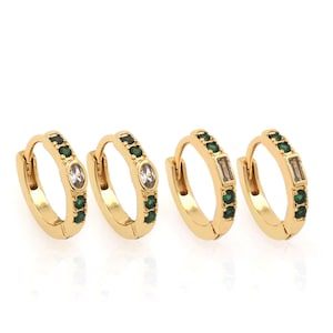 May include: Three gold hoop earrings with green and clear stones. The earrings are small and delicate.