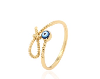 Puede incluir: Anillo de oro con un amuleto de ojo azul malvado y un diseño anudado.