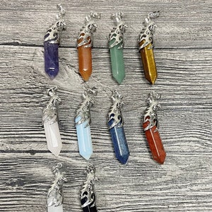 May include: Twelve silver pendant charms with different colored crystal points. The charms feature a decorative silver design around the top of each crystal point.