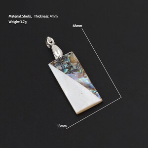 Puede incluir: Un colgante rectangular hecho de concha de abulón iridiscente con fondo blanco. El colgante mide 48 mm por 13 mm y tiene un grosor de 4 mm. Material: Conchas, Peso: 3,7 g