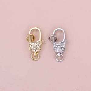 May include: Two silver and gold lobster clasps with clear crystal accents. The clasps are a popular jewelry making supply.