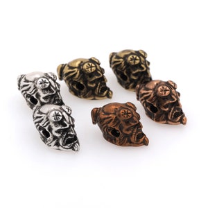 Peut inclure: Cinq perles en métal en forme de crâne de différentes couleurs, dont l'argent, l'or et le bronze. Les perles présentent des détails complexes et sont parfaites pour la fabrication de bijoux ou d'autres projets d'artisanat.