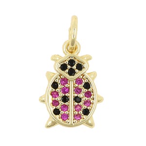 May include: Gold-toned ladybug charm with pink and black crystal accents. The charm has a loop at the top for attaching to a necklace or bracelet.