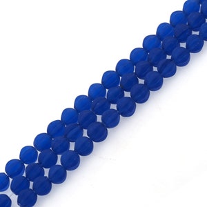 Peut inclure: Un brin de perles en verre bleu avec une surface facetée et texturée. Les perles sont rondes et ont une forme légèrement irrégulière.