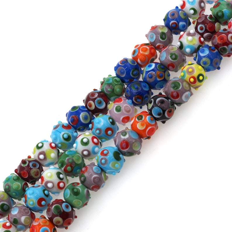 May include: A strand of colorful glass beads with a polka dot pattern. Each bead has a textured surface and is approximately 1 cm in diameter.