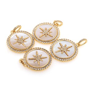 May include: Four gold-tone pendants with a white mother-of-pearl inlay and a starburst design set with clear rhinestones.