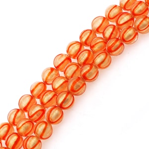May include: A strand of orange glass beads with gold accents. The beads have a swirl pattern and are round in shape.