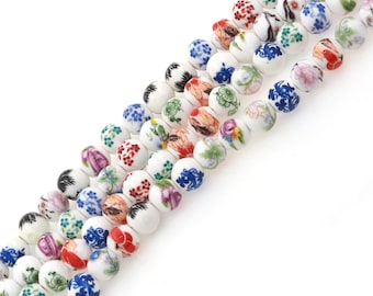 May include: A strand of white ceramic beads with colorful floral patterns. The beads are round and have a glossy finish.