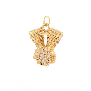May include: A gold-tone pendant featuring a detailed motorcycle engine design with a clear crystal center.