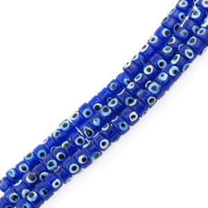 May include: A strand of blue glass beads with white and black evil eye designs. The beads are cylindrical and have a glossy finish.
