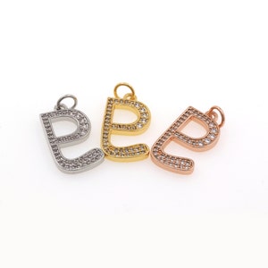 Puede incluir: Tres abalorios con la letra 'P', cada uno con un acabado metálico diferente: plata, oro y oro rosa. Cada abalorio está incrustado con piedras de circonita cúbica transparentes.