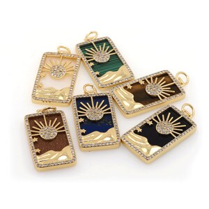 Peut inclure: Six pendentifs dorés avec un motif soleil et étoiles. Chaque pendentif présente une incrustation de pierre de couleur différente, notamment verte, marron, bleue, noire et blanche.