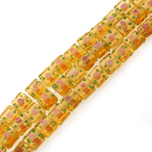 May include: A strand of square glass beads with a floral pattern in shades of yellow, orange, pink, and green.