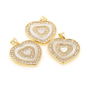 May include: Three gold heart-shaped pendants with white mother-of-pearl inlays and clear crystal accents.