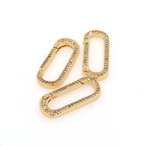 May include: Three gold-toned oval-shaped clasps with clear rhinestones encrusted around the edges.