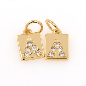 Peut inclure: Deux breloques dor&eacute;es de forme carr&eacute;e avec une lettre A en cristal transparent au centre. Chaque breloque a une boucle en haut pour l'attacher &agrave; un collier ou un bracelet.