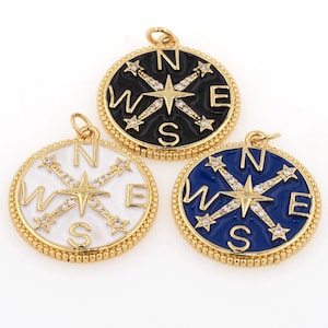 May include: Three gold-tone compass charms with black, white, and blue enamel. Each charm features a compass rose with a star in the center and the letters N, S, E, and W around the edge.