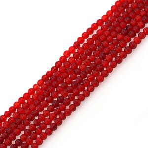 Può includere: Una collana di perline rotonde di vetro rosso brillante. Le perline sono lisce e lucide.