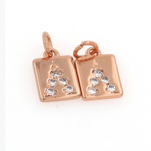 Peut inclure: Deux breloques dor&eacute;es avec la lettre "A" en strass transparents. Chaque breloque est de forme carr&eacute;e avec une boucle en haut pour l'attacher &agrave; un bracelet ou un collier.