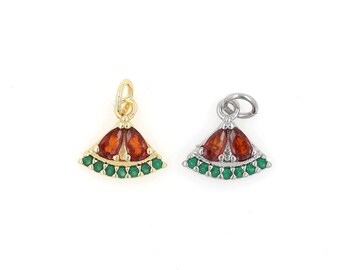 May include: Two gold and silver charm pendants with a fan shape, featuring red and green gemstones.