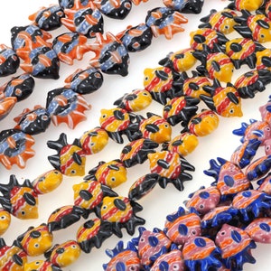 May include: A collection of colorful ceramic fish beads with black, red, yellow, orange, blue, and pink paint. The beads are in the shape of fish with fins and tails.