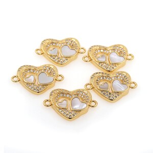 May include: Five gold-tone heart-shaped connectors with clear rhinestones and white mother-of-pearl accents. Each connector has two loops for attaching jewelry.