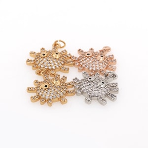 Puede incluir: Tres colgantes de amuleto en oro, oro rosa y plata, cada uno con un diseño de sol estilizado con una cara y brillantes pedrería.