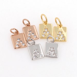 Peut inclure: Cinq pendentifs de charme avec la lettre 'A' sertie de strass transparents. Les pendentifs sont disponibles en diff&eacute;rentes finitions m&eacute;talliques : or, argent et or rose.