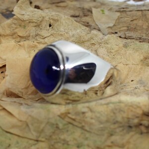 K&ouml;nnte beinhalten: Ein silberner Ring mit einem gro&szlig;en, runden, dunkelblauen Edelstein.