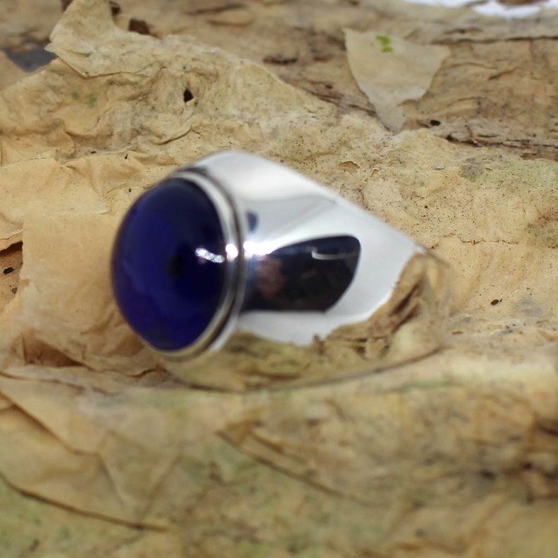 K&ouml;nnte beinhalten: Ein silberner Ring mit einem gro&szlig;en, runden, dunkelblauen Edelstein.