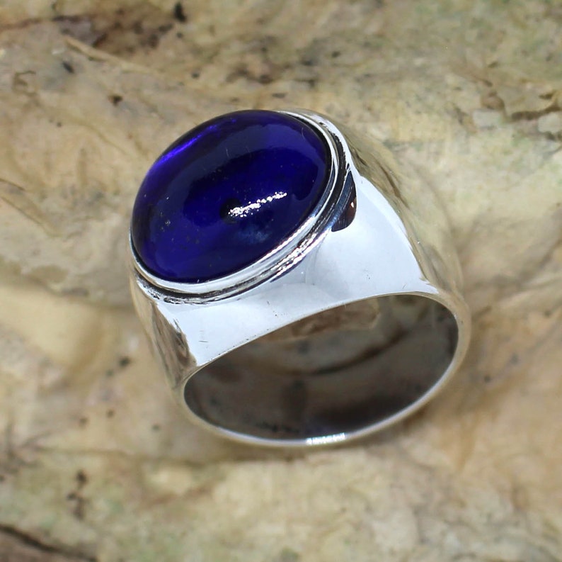 K&ouml;nnte beinhalten: Ein silberner Ring mit einem gro&szlig;en, ovalen, dunkelblauen Edelstein, der in der Mitte eingesetzt ist.