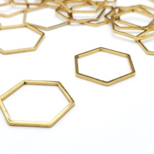 May include: A group of gold-colored metal hexagonal rings, some stacked on top of each other, on a white surface.