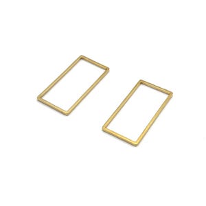 Op de afbeelding: Twee goudkleurige rechthoekige metalen frames. De frames zijn van binnen leeg en hebben een eenvoudig, minimalistisch ontwerp. Het zijn waarschijnlijk onderdelen voor het maken van sieraden of andere knutselprojecten.