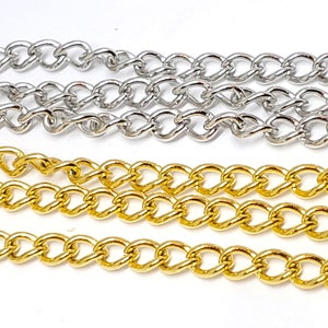 May include: Close-up of silver and gold curb chains. The chains are made of interlocking oval links. The silver chains are at the top, and the gold chains are at the bottom. The chains are likely used for jewellery making.