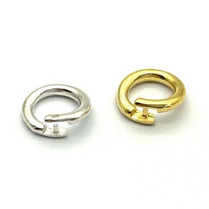 Peut inclure: Deux anneaux de jonction, l'un en argent et l'autre en or, avec une petite boucle sur le côté. Les anneaux sont ouverts et prêts à être attachés à une chaîne ou à d'autres bijoux.